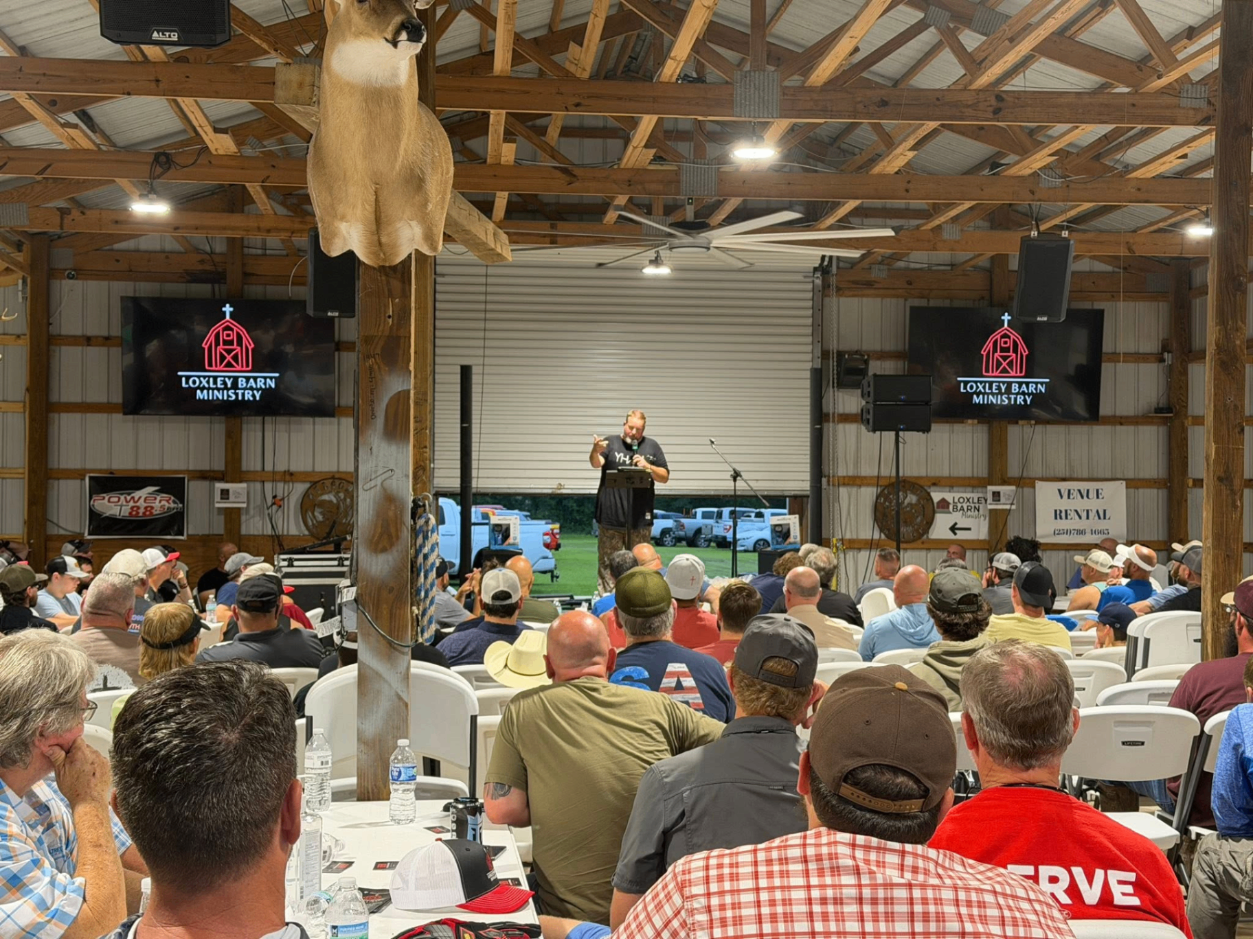 Speaker on stage with packed crowd at The Loxley Barn